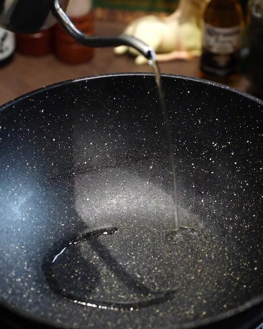 Aceite de cocina vertido en una sartén negra vacía precalentada.