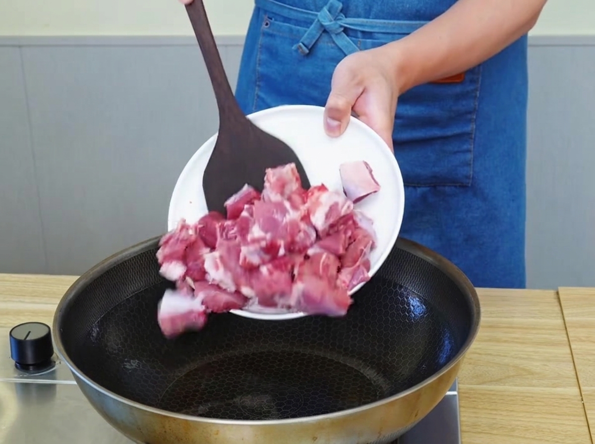Trozos de ternera dorándose en una sartén con aceite caliente.