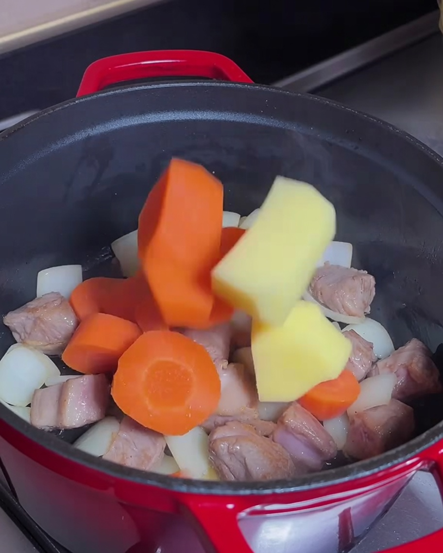 Zanahorias y patatas mezcladas en la olla con la carne dorada.