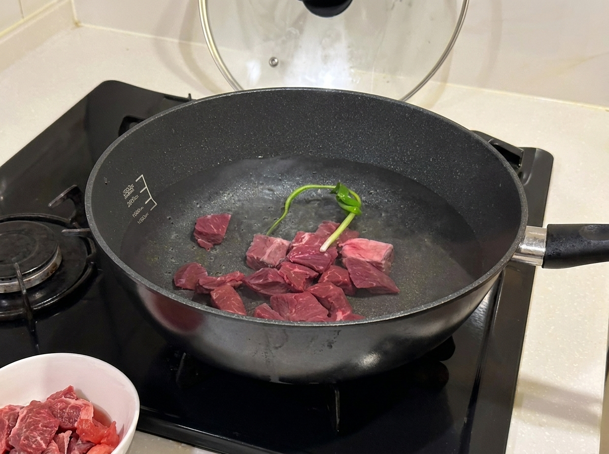 Trozos de ternera hirviendo en una olla con aromáticos y vino.