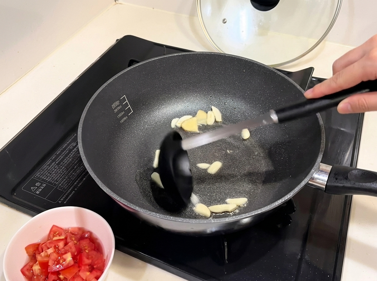 Trozos de cebolla roja ablandándose en la sartén con el ajo.