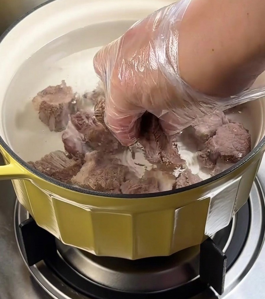 Olla con falda de res cocinándose a fuego lento bajo una tapa.