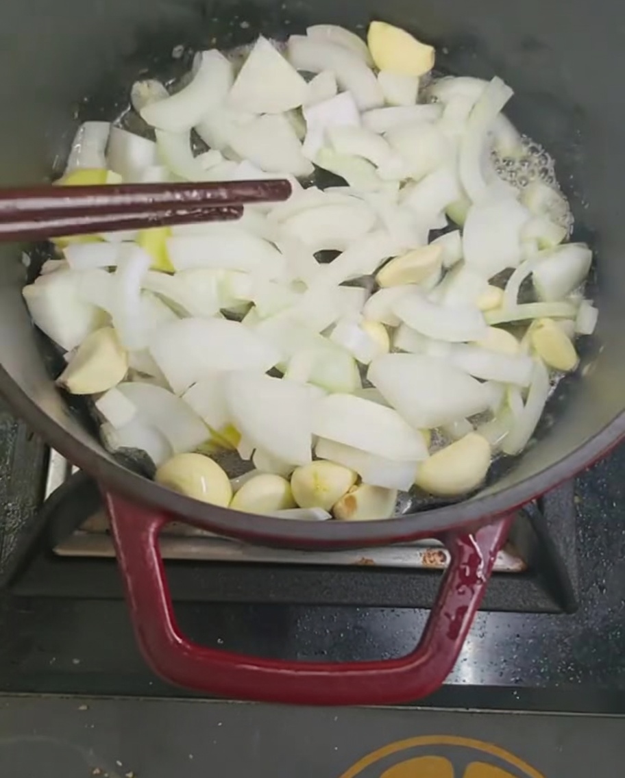 Salteando trozos de cebolla y ajo en una olla con palillos.