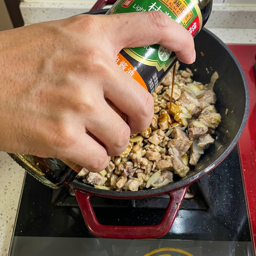 Vertiendo salsa de soja desde una botella a la olla con la carne.