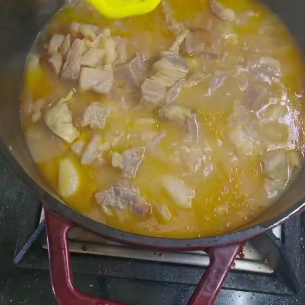 Trozos de zanahoria y patata añadidos al estofado de ternera hirviendo en la olla.
