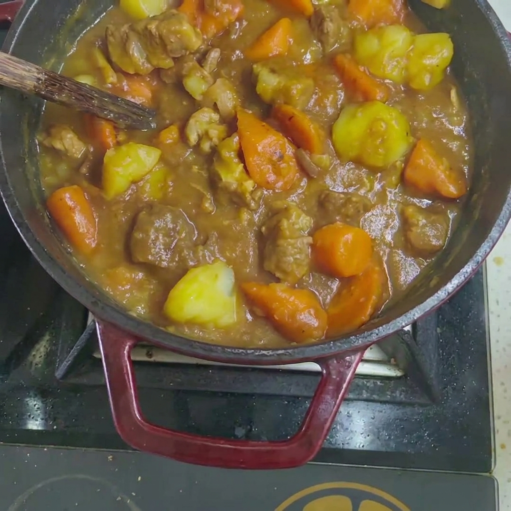 Pastillas de curry sólidas cayendo en el estofado de carne y verduras cocidas.