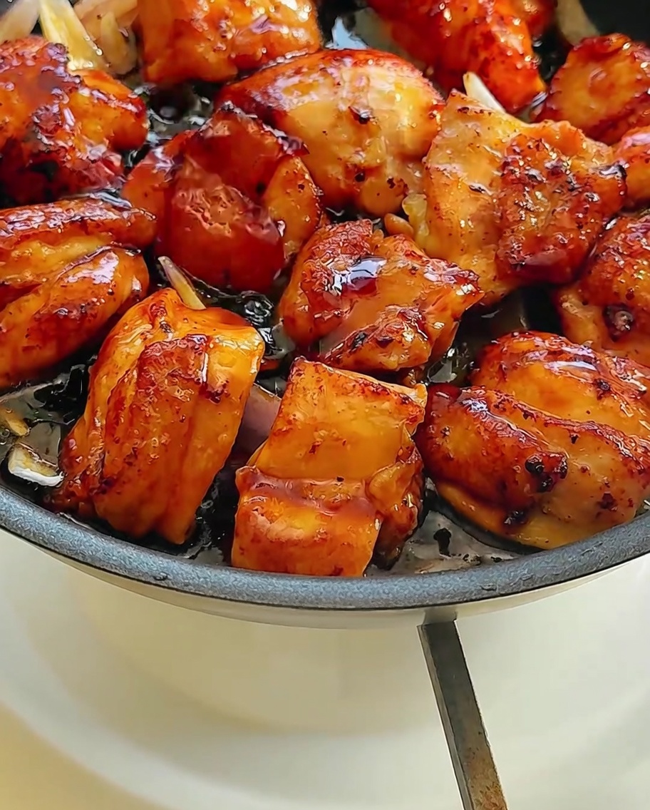 La mezcla de pollo y cebolla siendo cubierta por una salsa oscura y sabrosa.