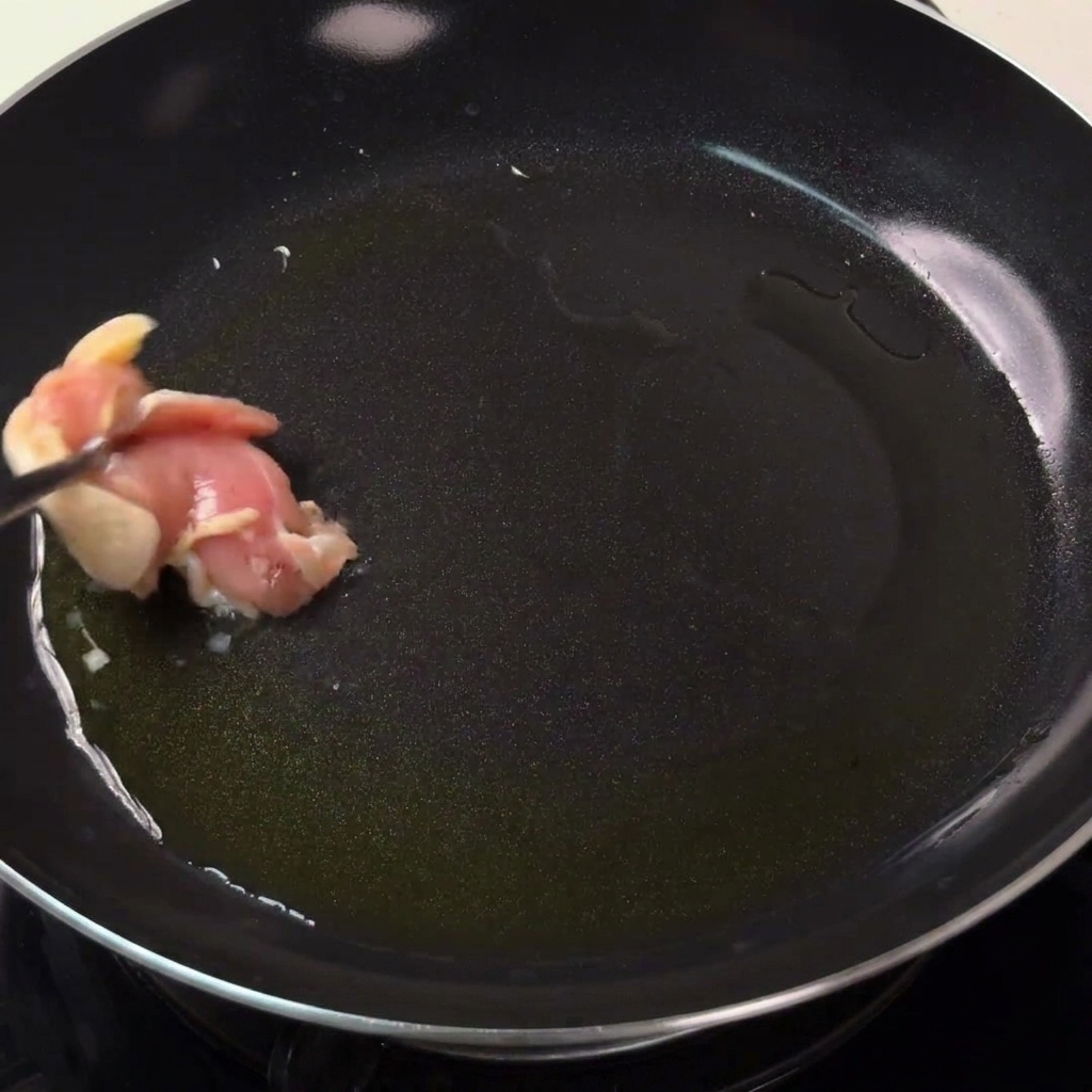 Trozos de pollo dorándose en una sartén caliente con aceite.