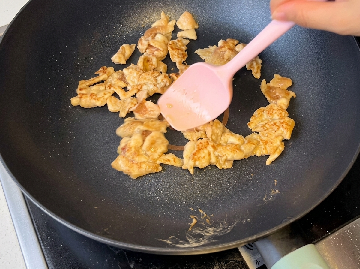 Cebollas en rodajas siendo salteadas junto al pollo dorado en la sartén.