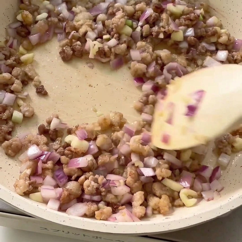 Especias siendo añadidas a la sartén con la carne picada y la cebolla.