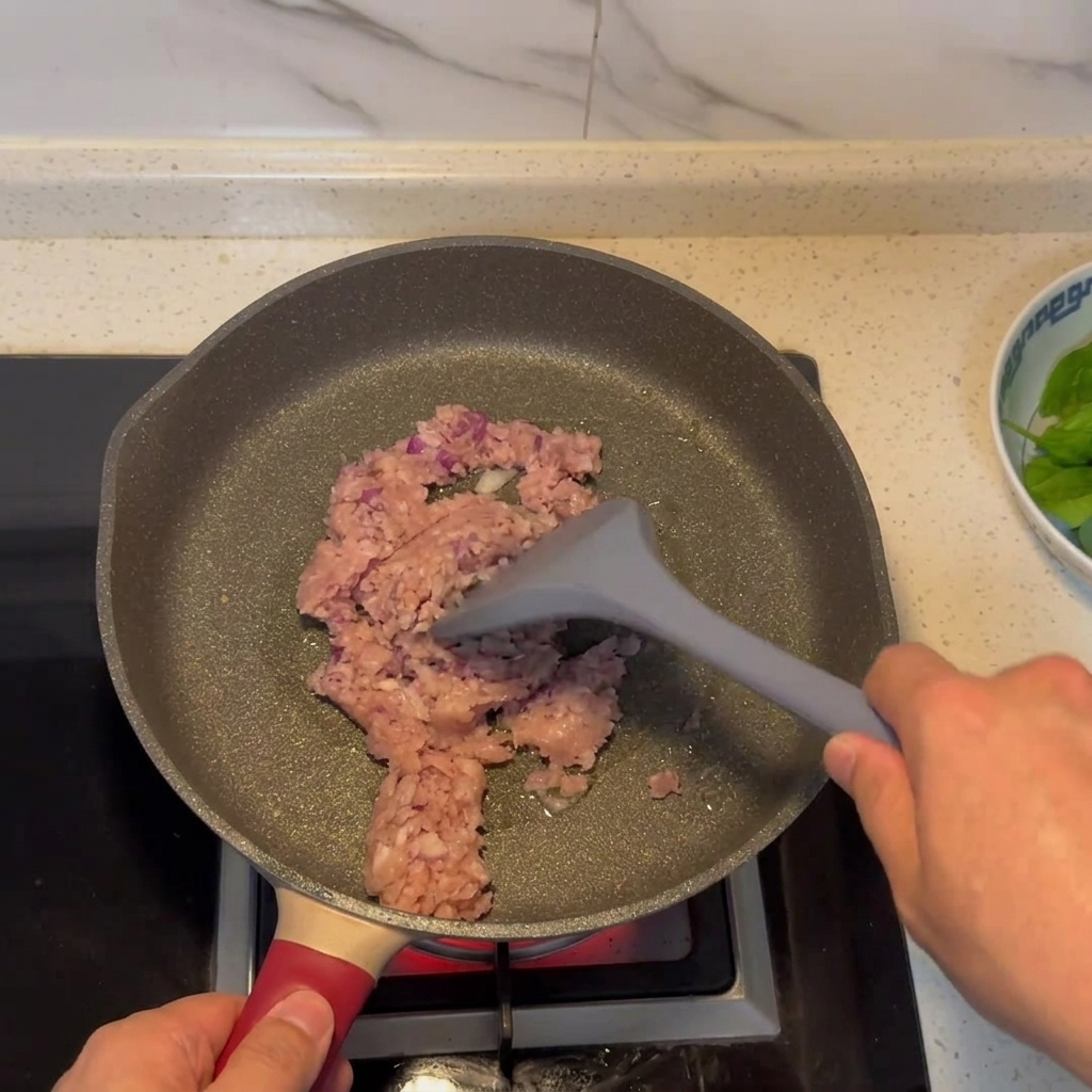 Mezcla de carne picada y cebolla dorándose en una sartén.