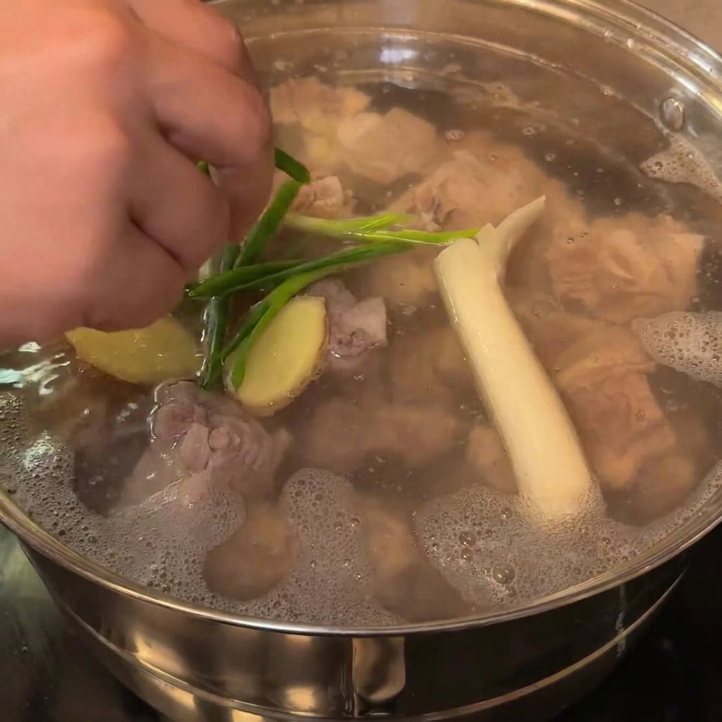 Primer plano de trozos de cebolla blanca y tallos de cebollino siendo añadidos a la olla.