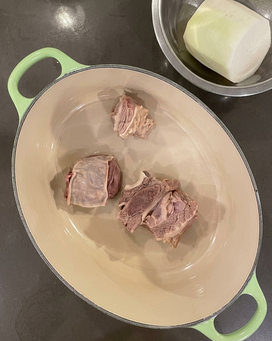 Costillas limpias dispuestas en el fondo de una olla de hierro fundido vacía.