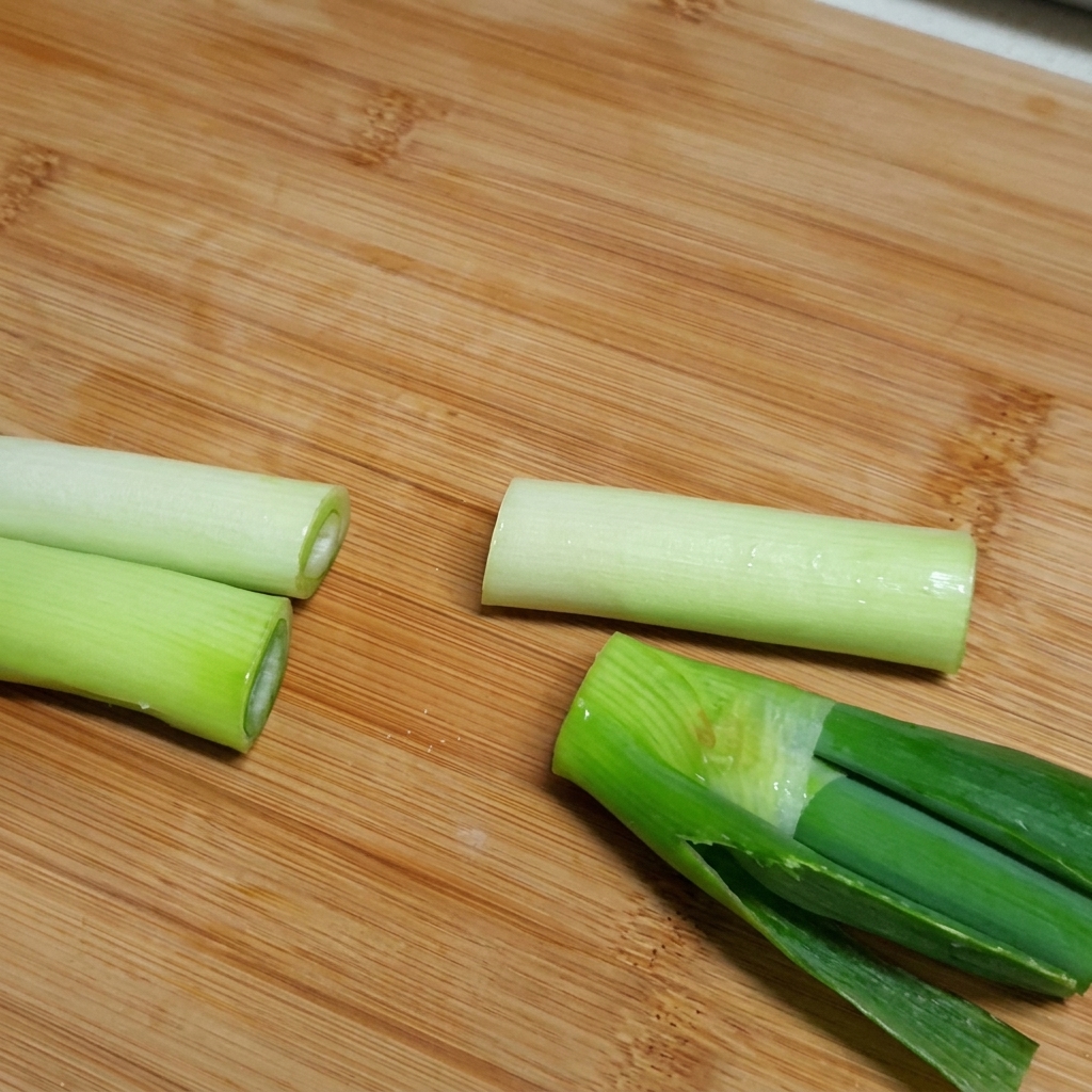 Ingredientes incluyendo costillas de res, rábano y trozos de cebolla siendo añadidos a una olla grande llena de agua.