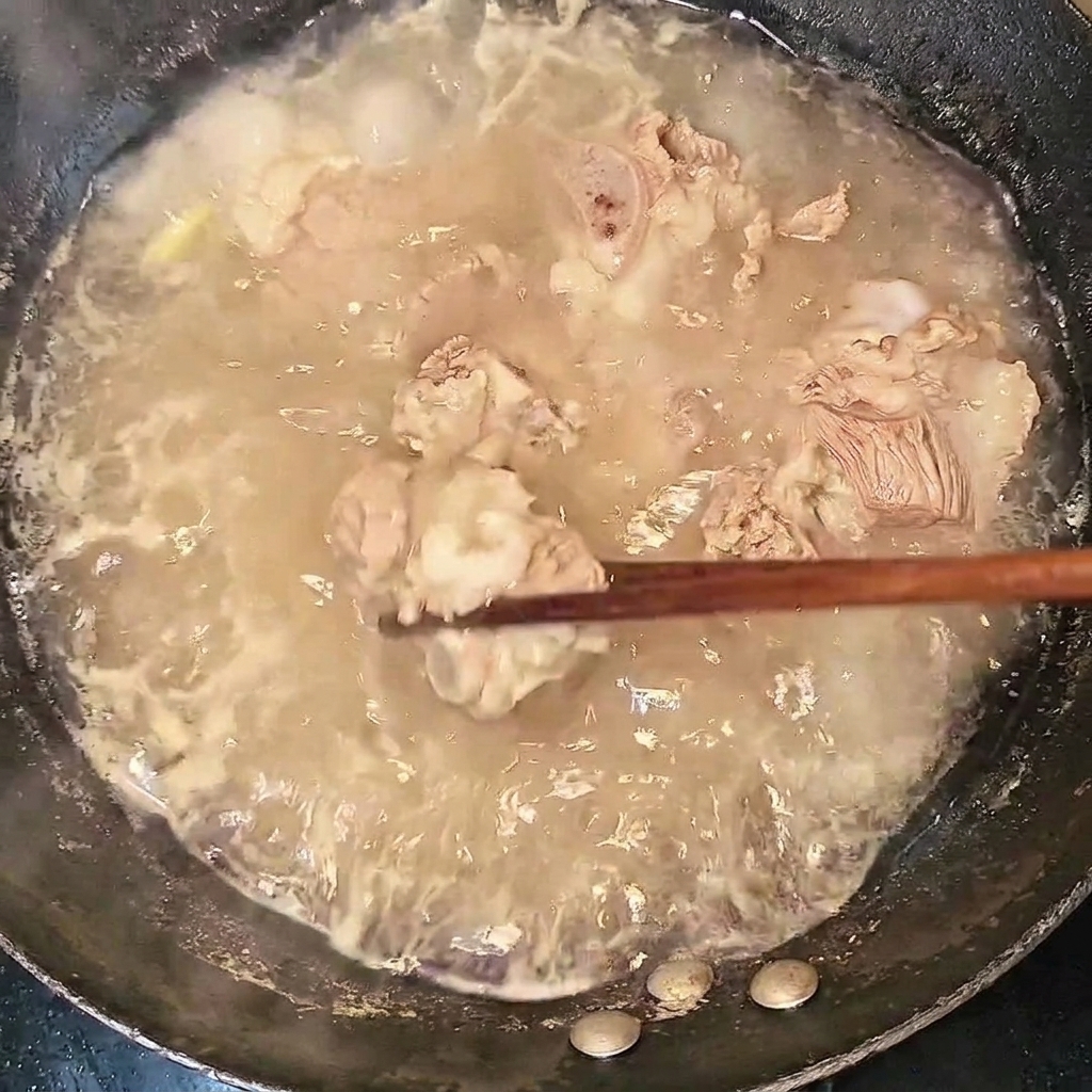 Costillas de res blanqueadas siendo retiradas del agua hirviendo con palillos.