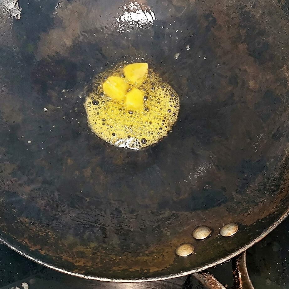 Costillas de res y rodajas de jengibre salteándose en un wok caliente.