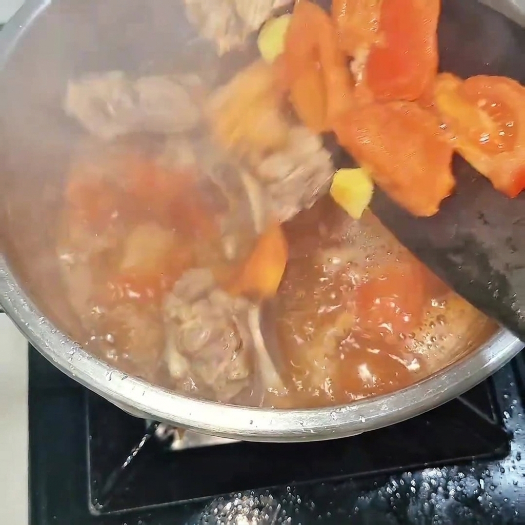 La mezcla de costillas de res y tomate siendo vertida en una olla a presión de acero, lista para ser cerrada.