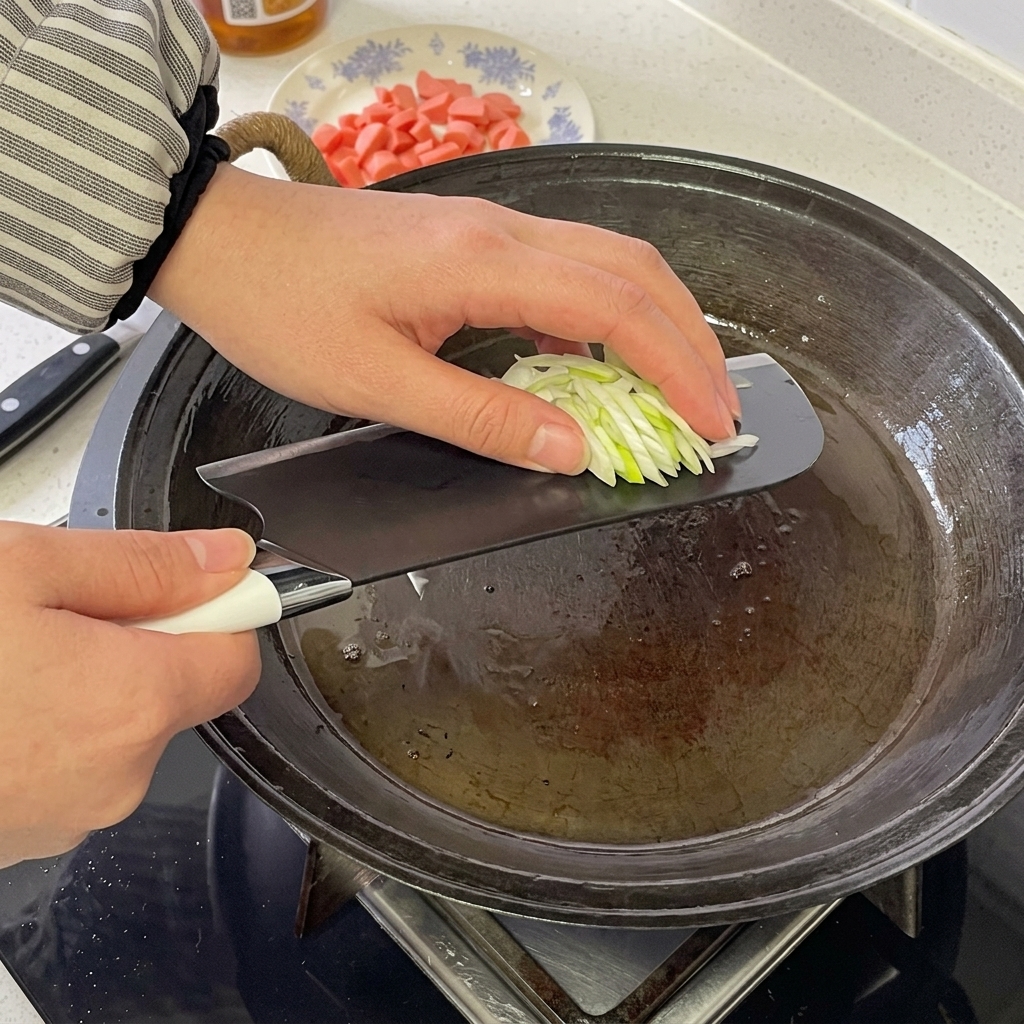 Rodajas de salchicha y cebolleta picada chisporroteando y siendo revueltas juntas en una sartén caliente.