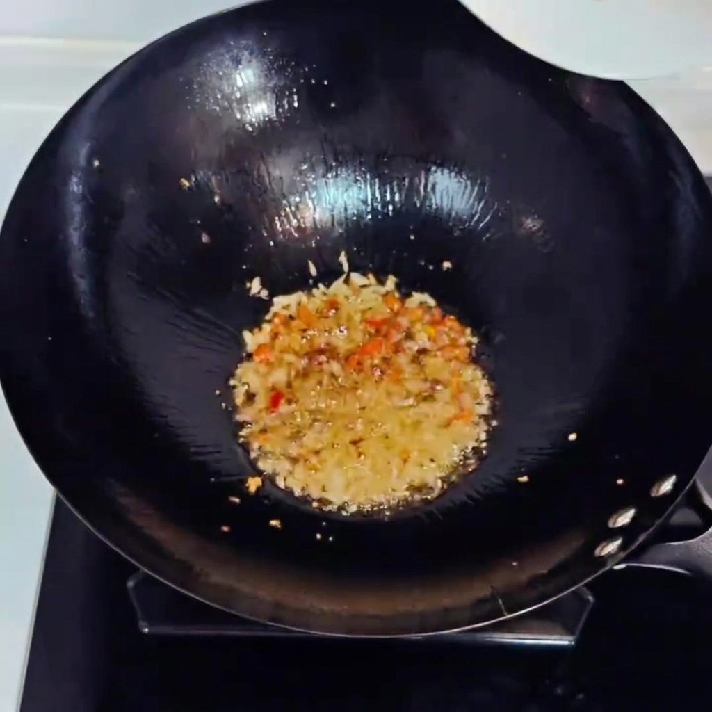 Kimchi picado y jamón en dados siendo salteados en un wok con los aromáticos.