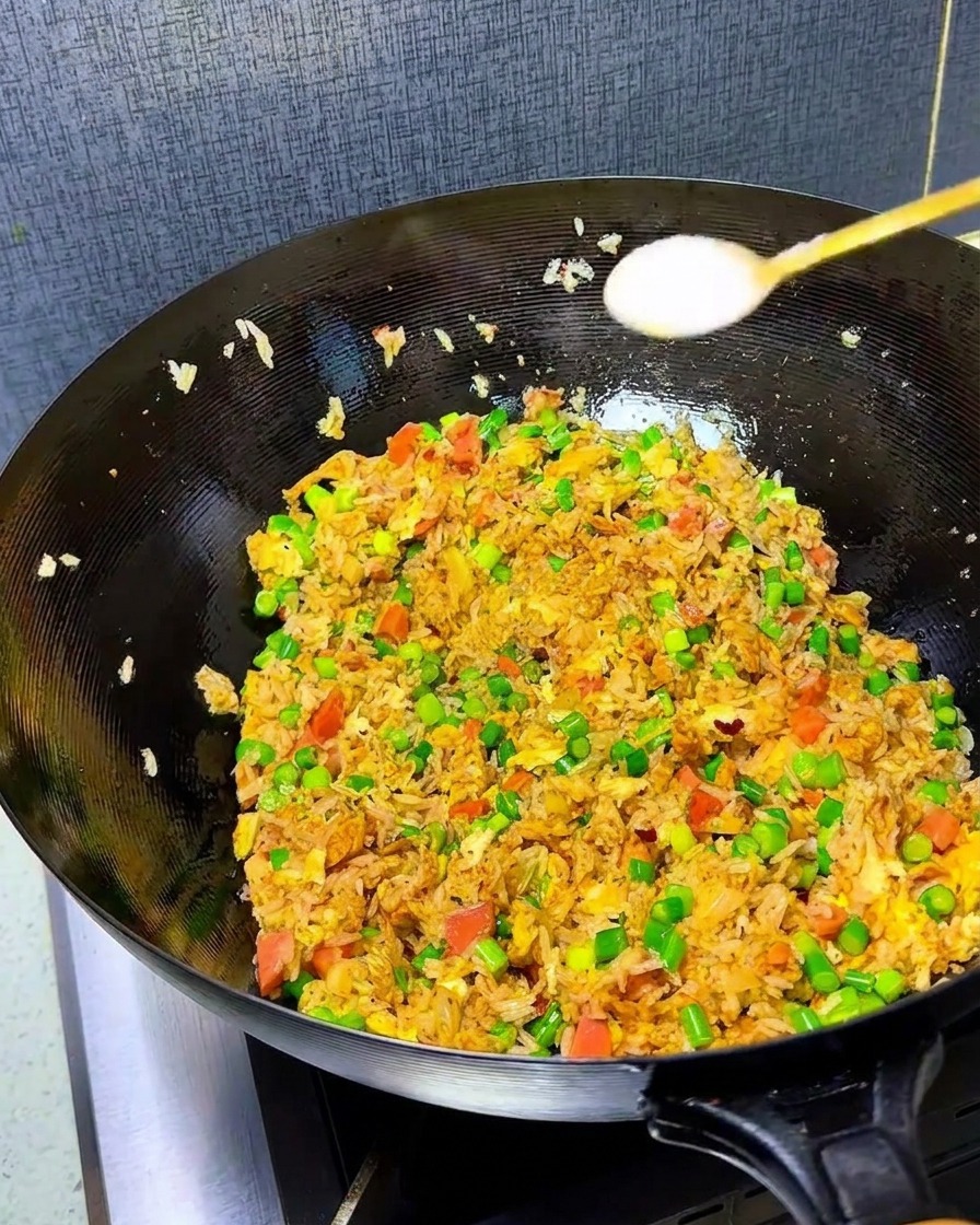 Primer plano de sal y caldo de pollo siendo espolvoreados sobre el arroz frito en el wok.