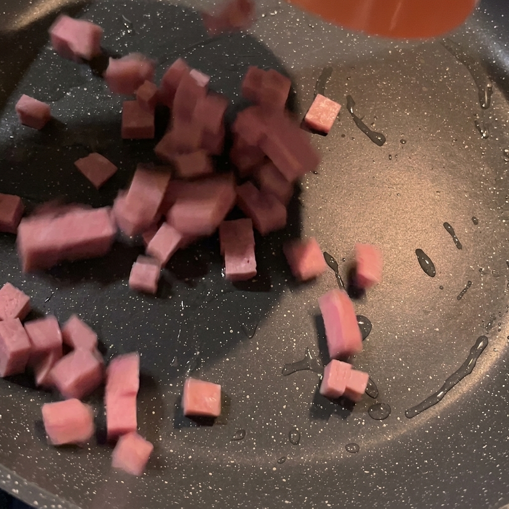 Trozos de spam en cubos friéndose y dorándose en una sartén caliente.