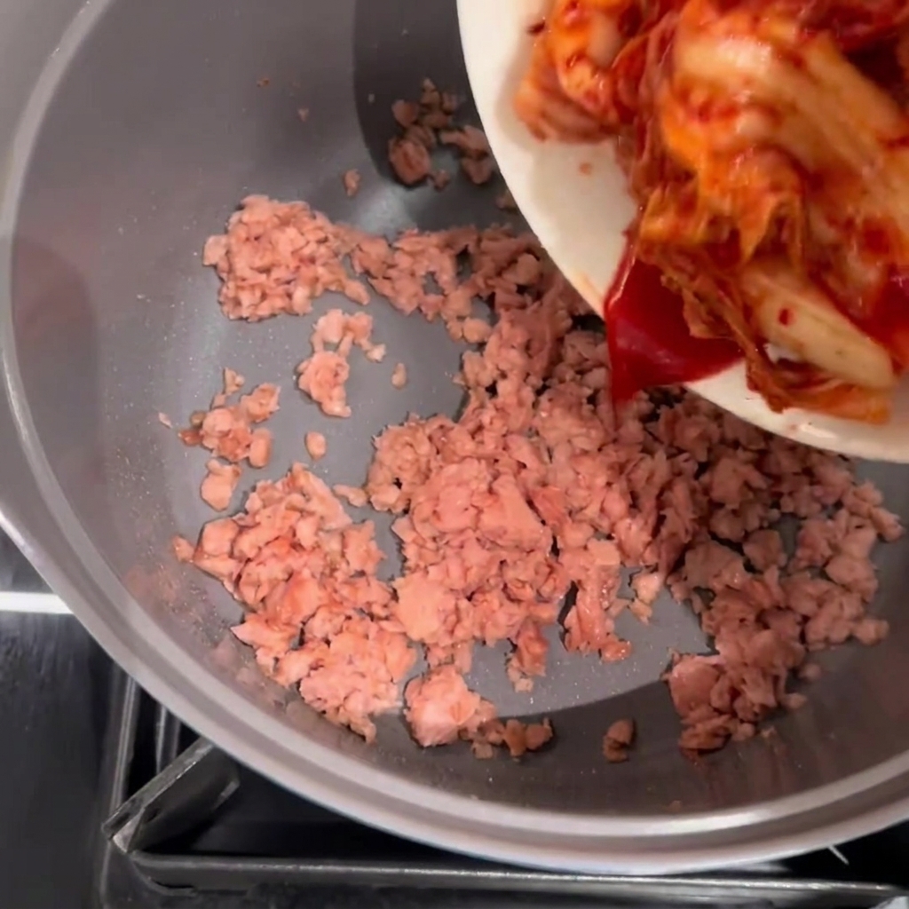 Kimchi añadido a una olla con Spam dorado.