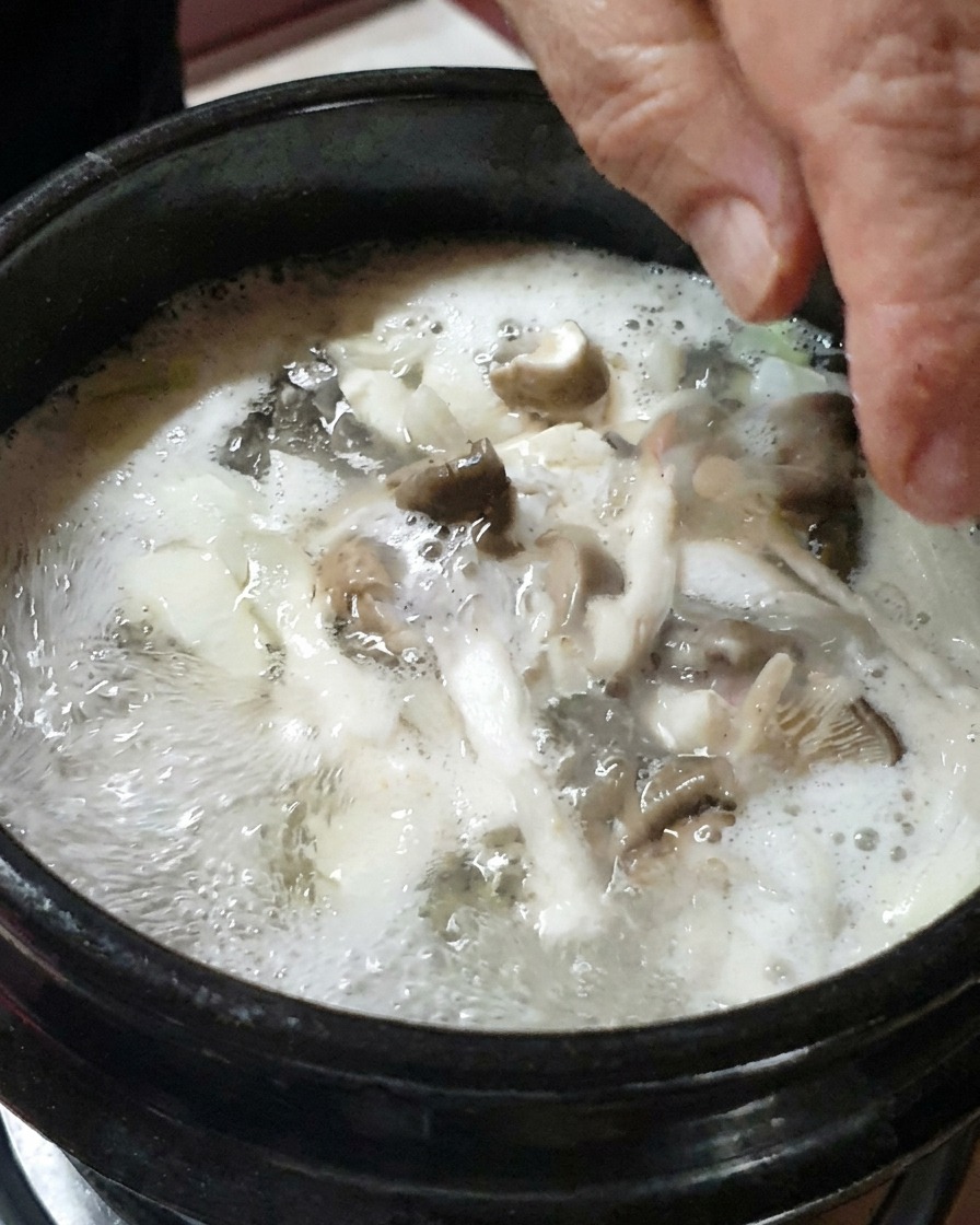 Cebollas picadas y champiñones laminados siendo añadidos al estofado.