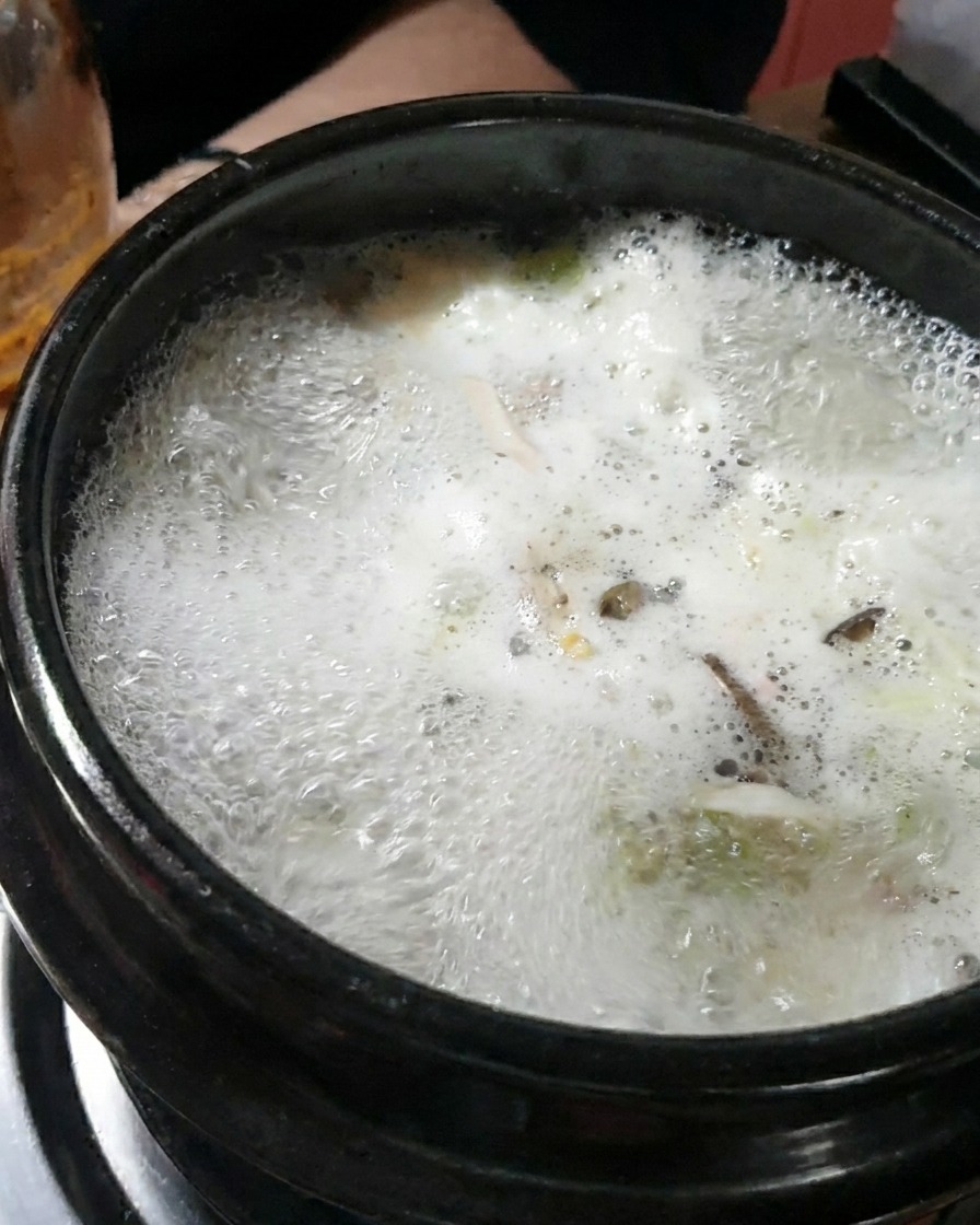 Una gran cucharada de pasta de soja espesa siendo disuelta en el caldo hirviendo.