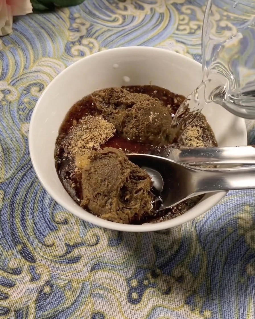 Brotes de soja frescos cubriendo el fondo de una olla de barro oscura con rebanadas de pescado abadejo colocadas encima.