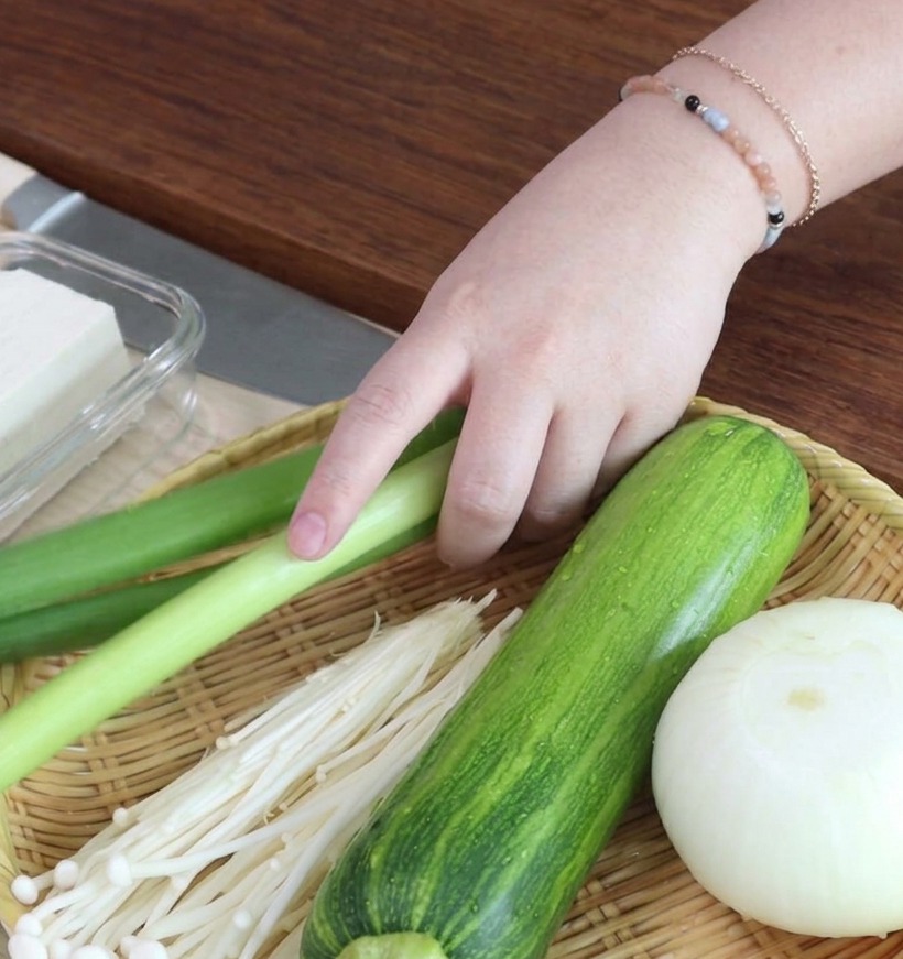 Aros de cebolleta finamente cortados dispuestos sobre una tabla de madera.