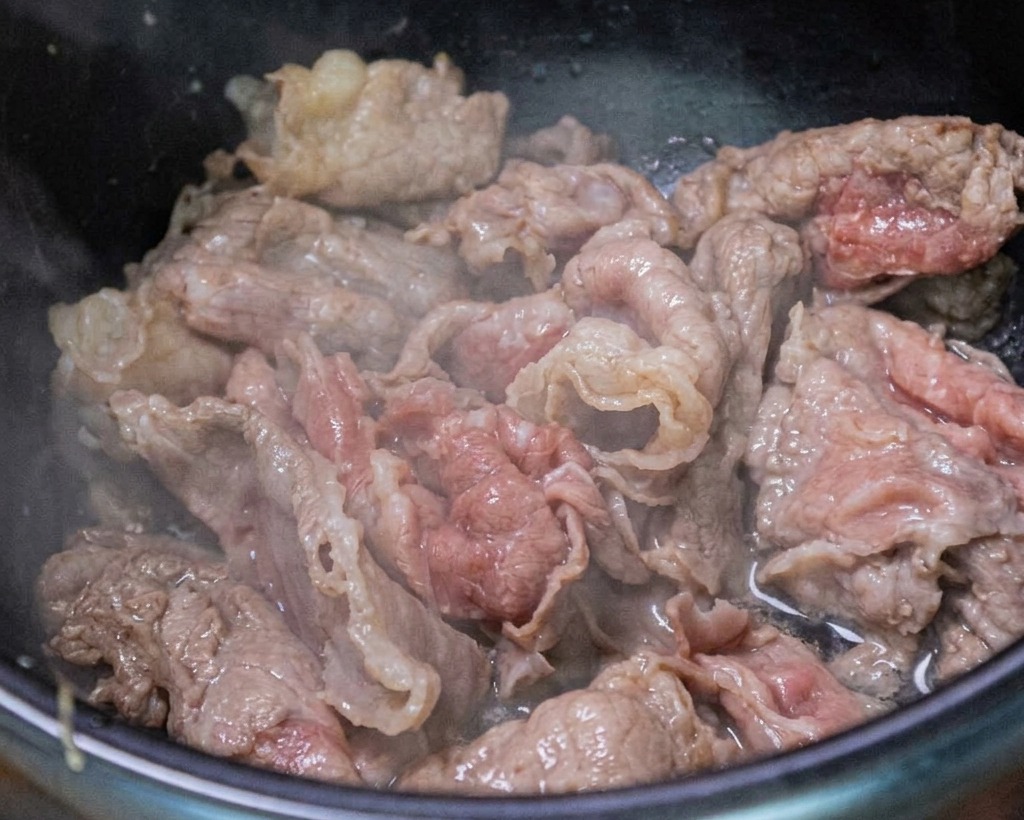 Ternera siendo salteada con ajo picado y cebolleta.