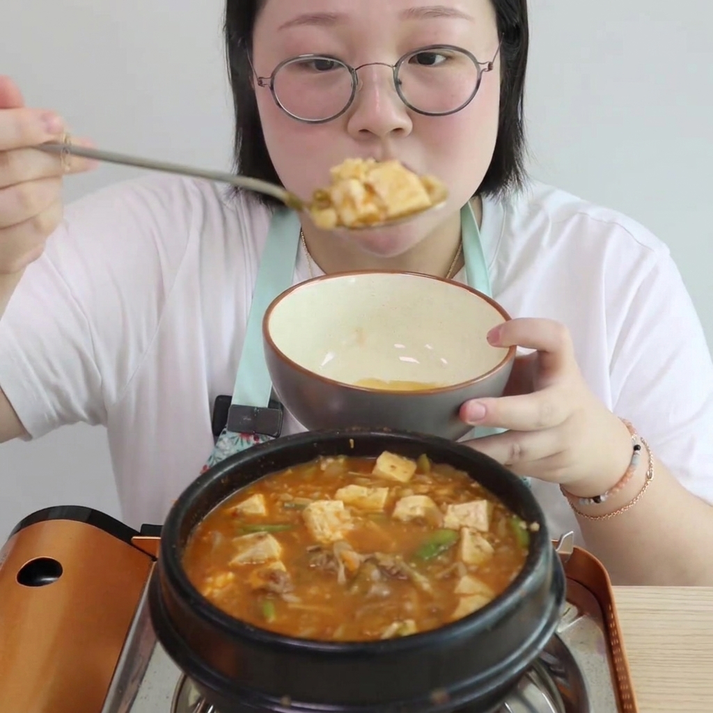 Tofu en cubos y setas enoki siendo añadidos al estofado.