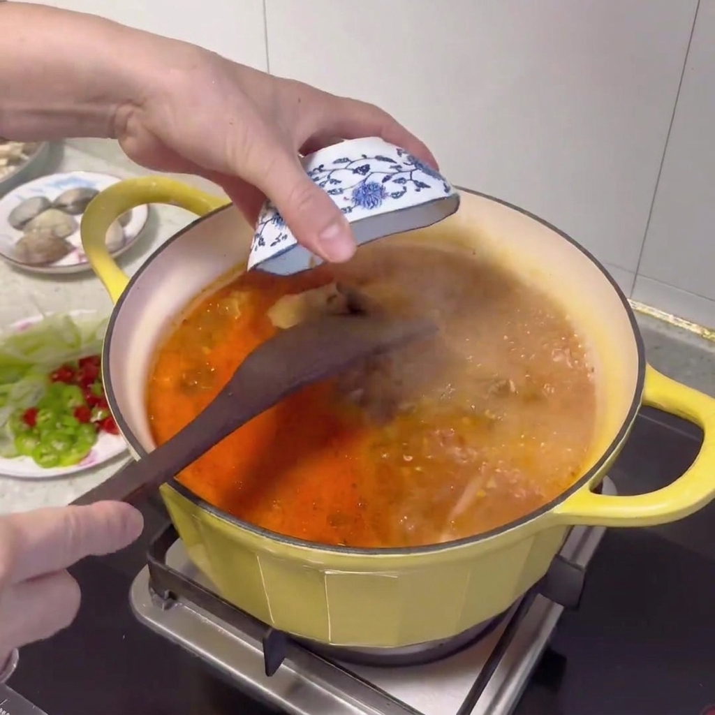 Una cuchara de madera añadiendo pasta de soja coreana al caldo burbujeante.