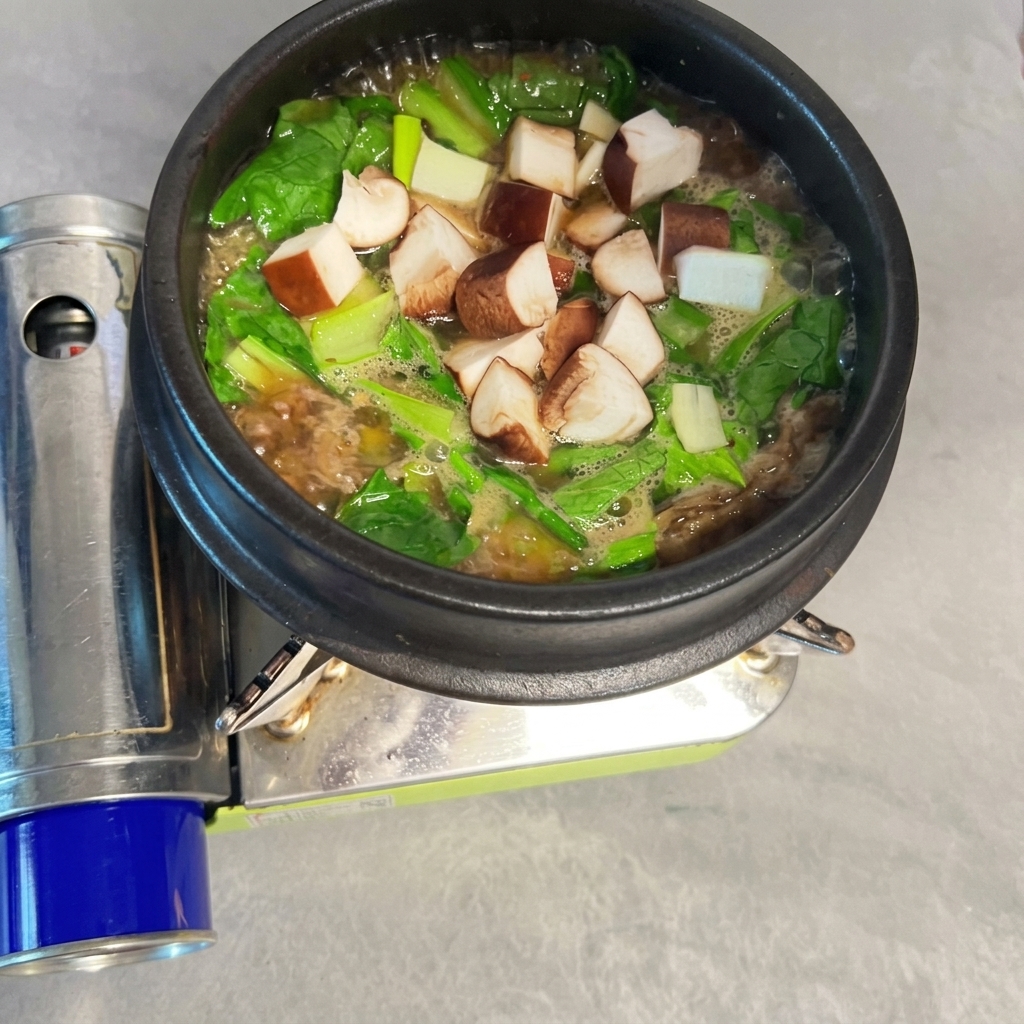 Setas shiitake picadas esparcidas en el Doenjang-jjigae hirviendo.