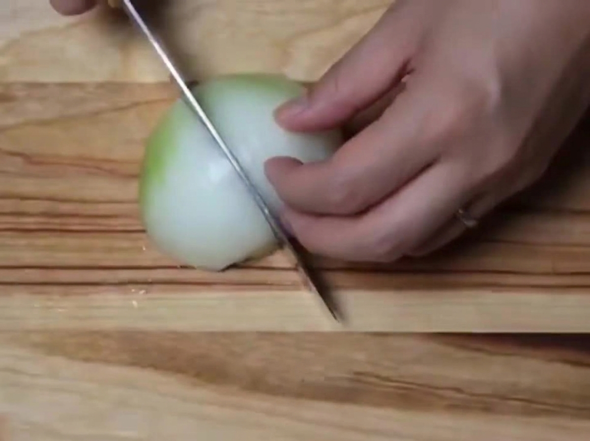 Una cebolla blanca picada en trozos pequeños sobre una tabla de madera.