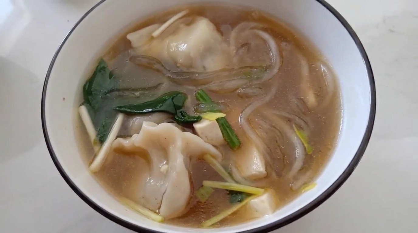 Sopa reconfortante de dumplings con fideos vermicelli y espinacas