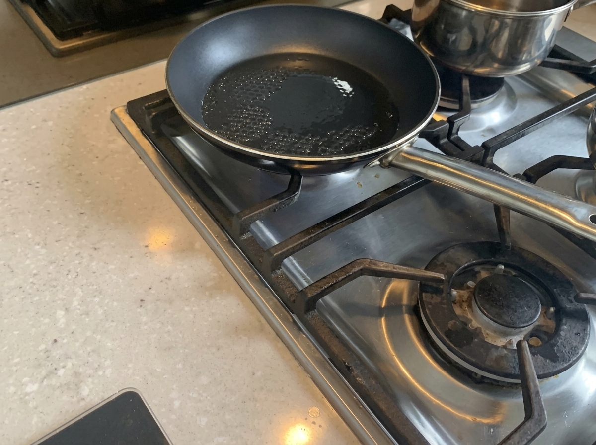Cebolla picada siendo salteada en una sartén con aceite caliente hasta ablandarse.