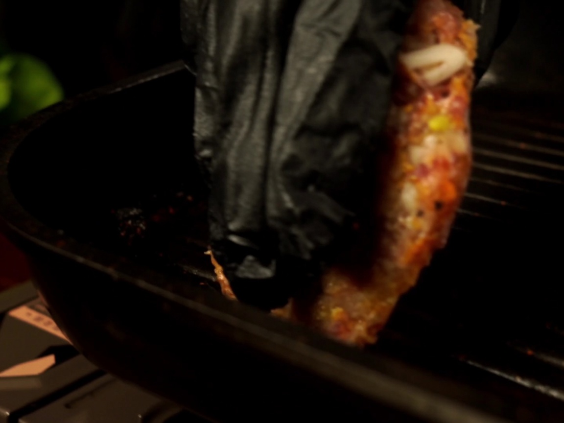 Una hamburguesa cruda siendo colocada en una sartén grill precalentada.