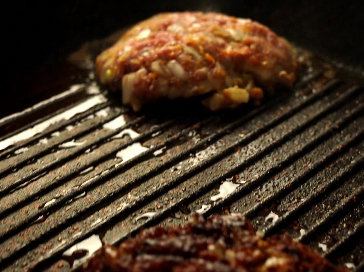 Primer plano de una hamburguesa Wagyu siendo girada con una espátula en la sartén.