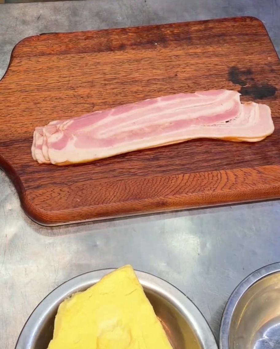 Trozos de bacon ahumado en rodajas sobre una tabla de cortar de madera.