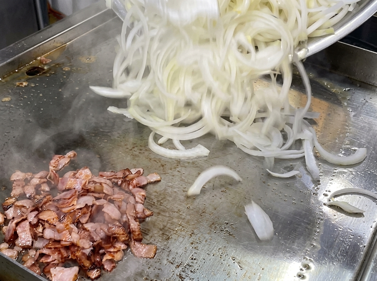 Un montón de cebollas blancas crudas cortadas finamente vertidas sobre una plancha junto a bacon cocinado.