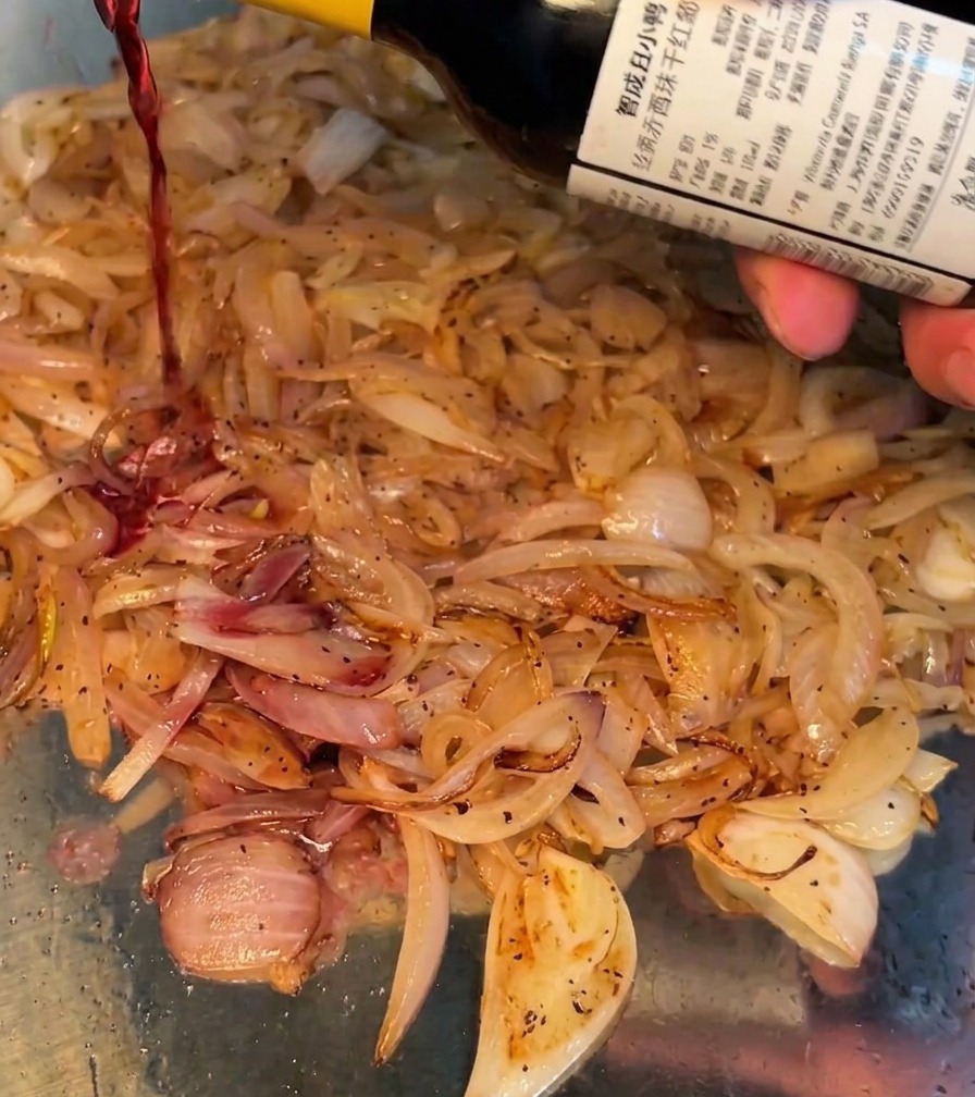 Vino tinto vertiéndose en la sartén con las cebollas salteadas.