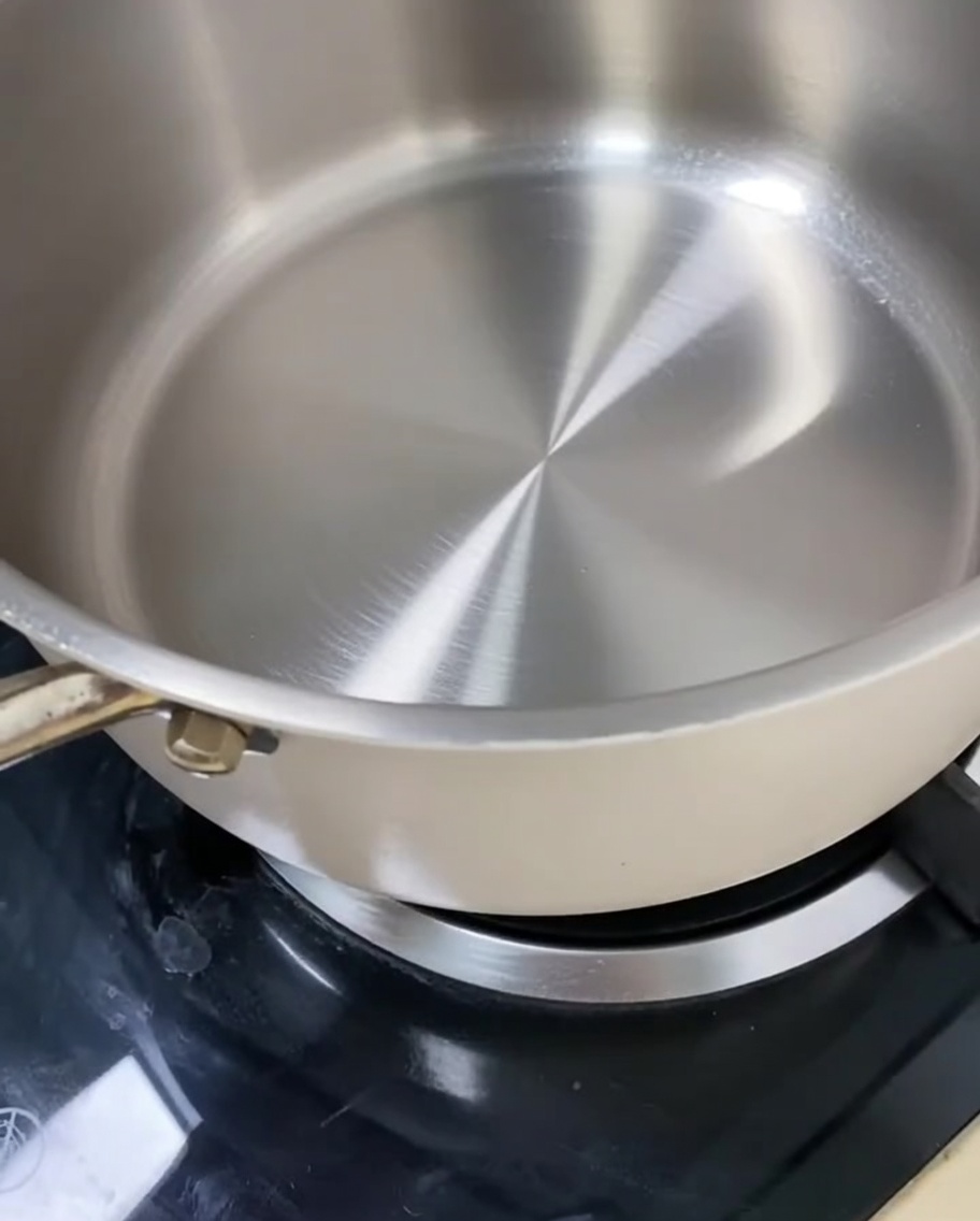 Azúcar piedra y azúcar blanca derritiéndose lentamente en una sartén para crear una base de caramelo.