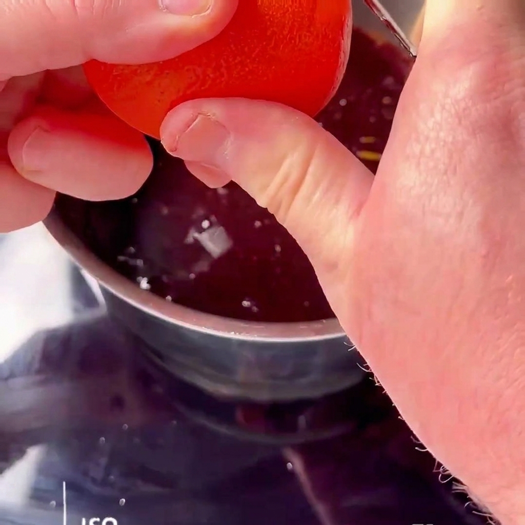 Jugo de naranja fresco siendo exprimido sobre una salsa de cereza roja hirviendo.