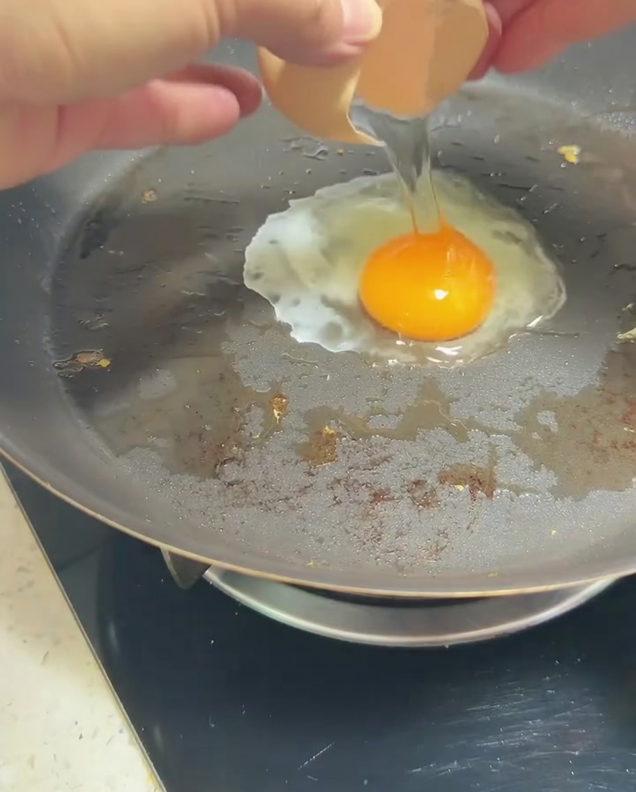 Un huevo friéndose en una sartén con una yema dorada.
