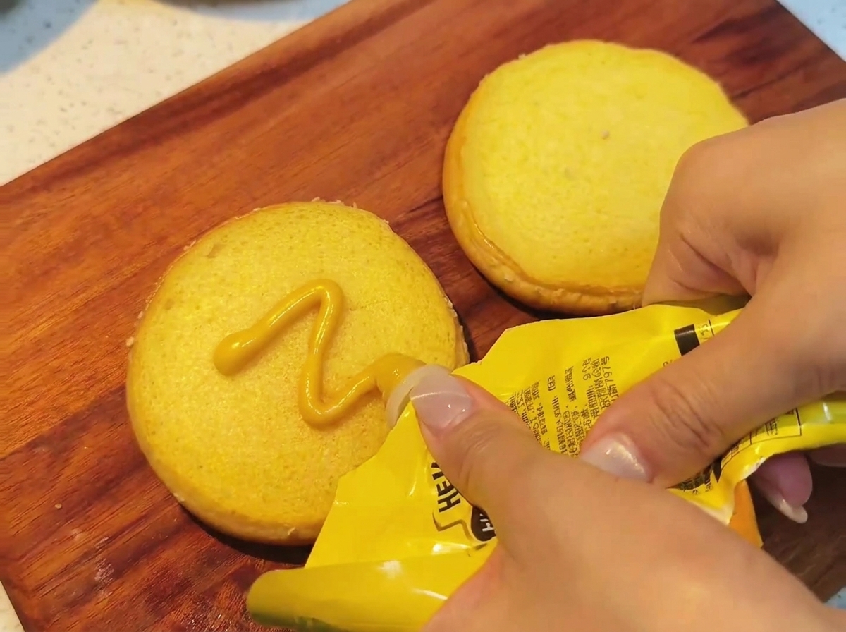 Mostaza con miel siendo extendida sobre un pan tostado.