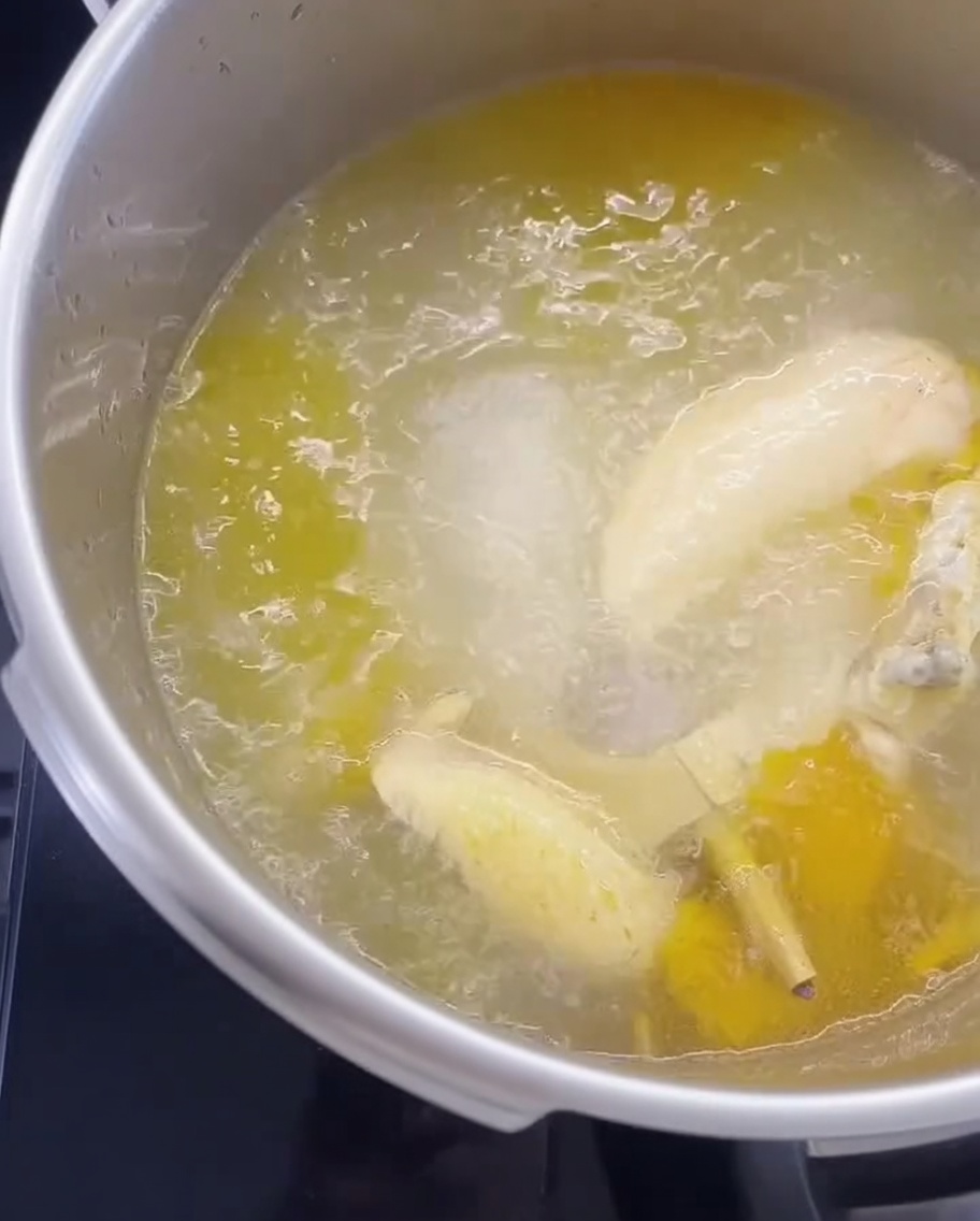 Fideos secos sumergidos en una olla con caldo de pollo hirviendo.