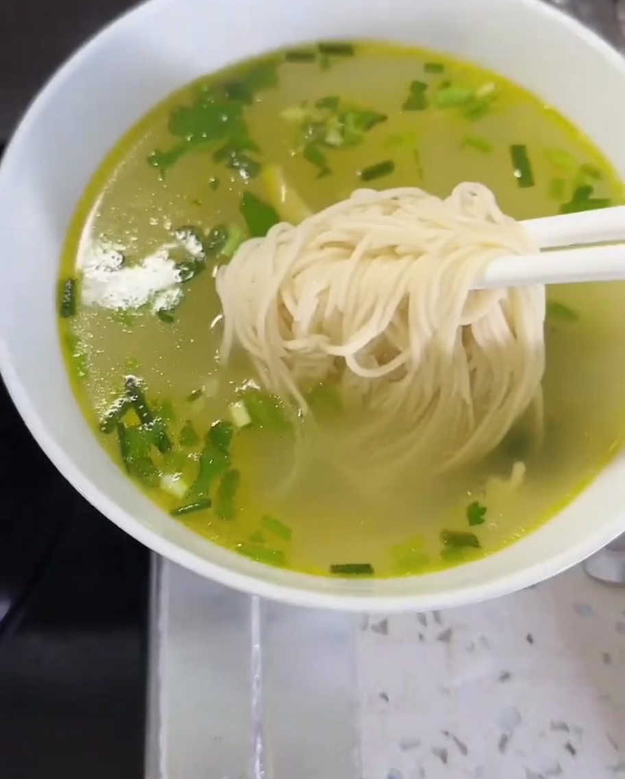 Fideos y verduras transferidos a un tazón con caldo para completar el plato.