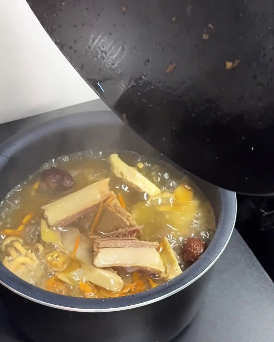 Trasvasando la sopa de pollo y setas del wok a la olla arrocera.