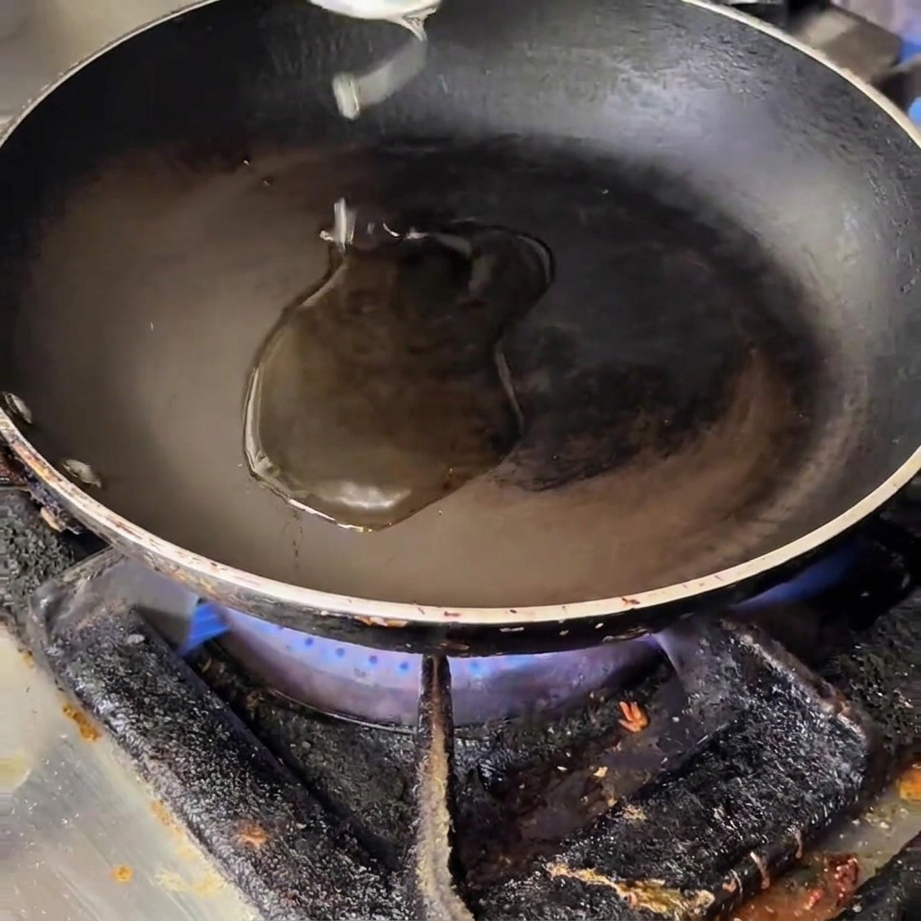 Cebolla, ajo, tocino, champiñones y trozos de espárragos siendo salteados en una sartén caliente con aceite.